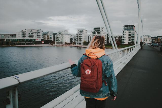 vrouw met rugzak loopt over een brug in de stad