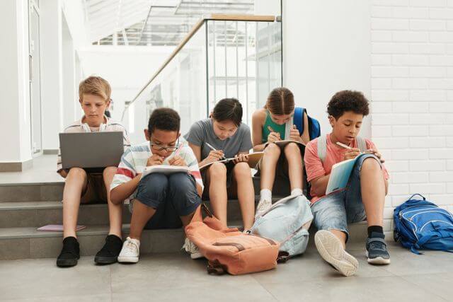 Middelbare scholieren op de trap met rugzak en laptop